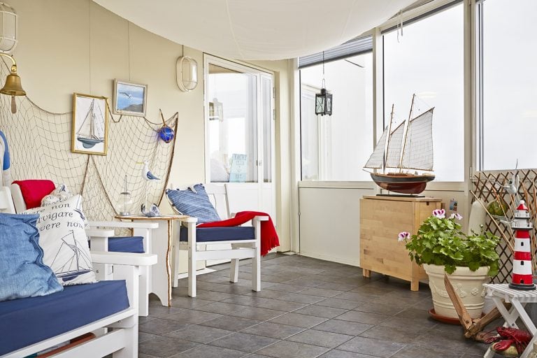 marint tema: vita stolar med blå dynor, nät och båtbild på väggen, modellskepp