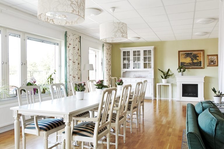 vitt långt matbord,stolar med vit-blårandiga dynor, stora fönster