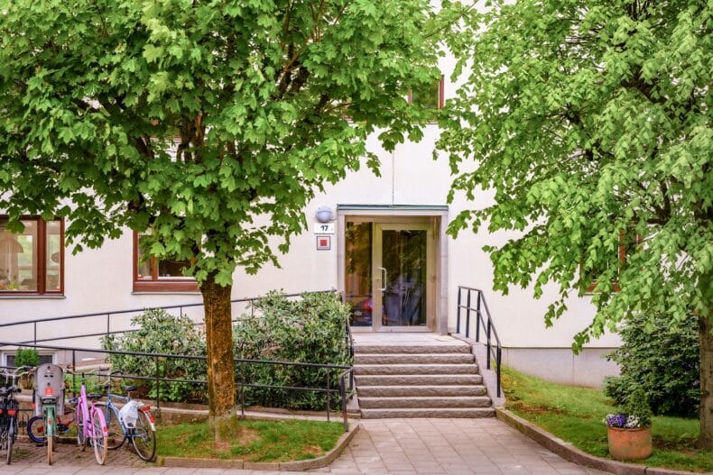 Port i byggnad med gröna träd i förgrunden