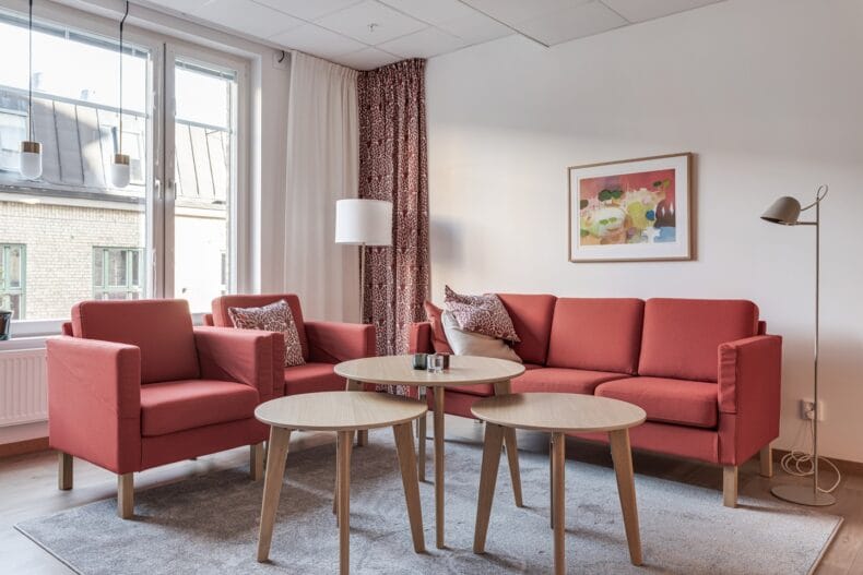 Soffgrupp med tre runda bord framför och tavla på väggen.