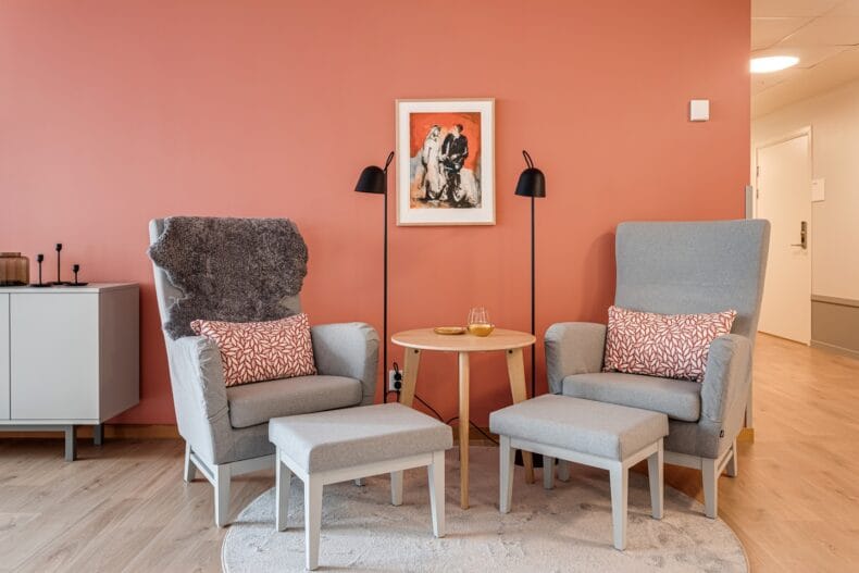 Två fåtöljer med fotpallar. På vänstra fåtöljer hänger en fårskinnspläd.