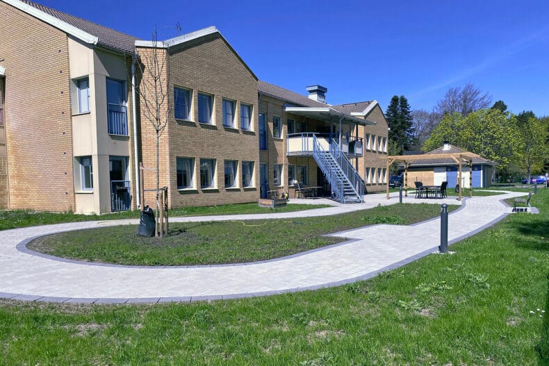 Fasad ljusbrun tegel byggnad med väg i förgrunden